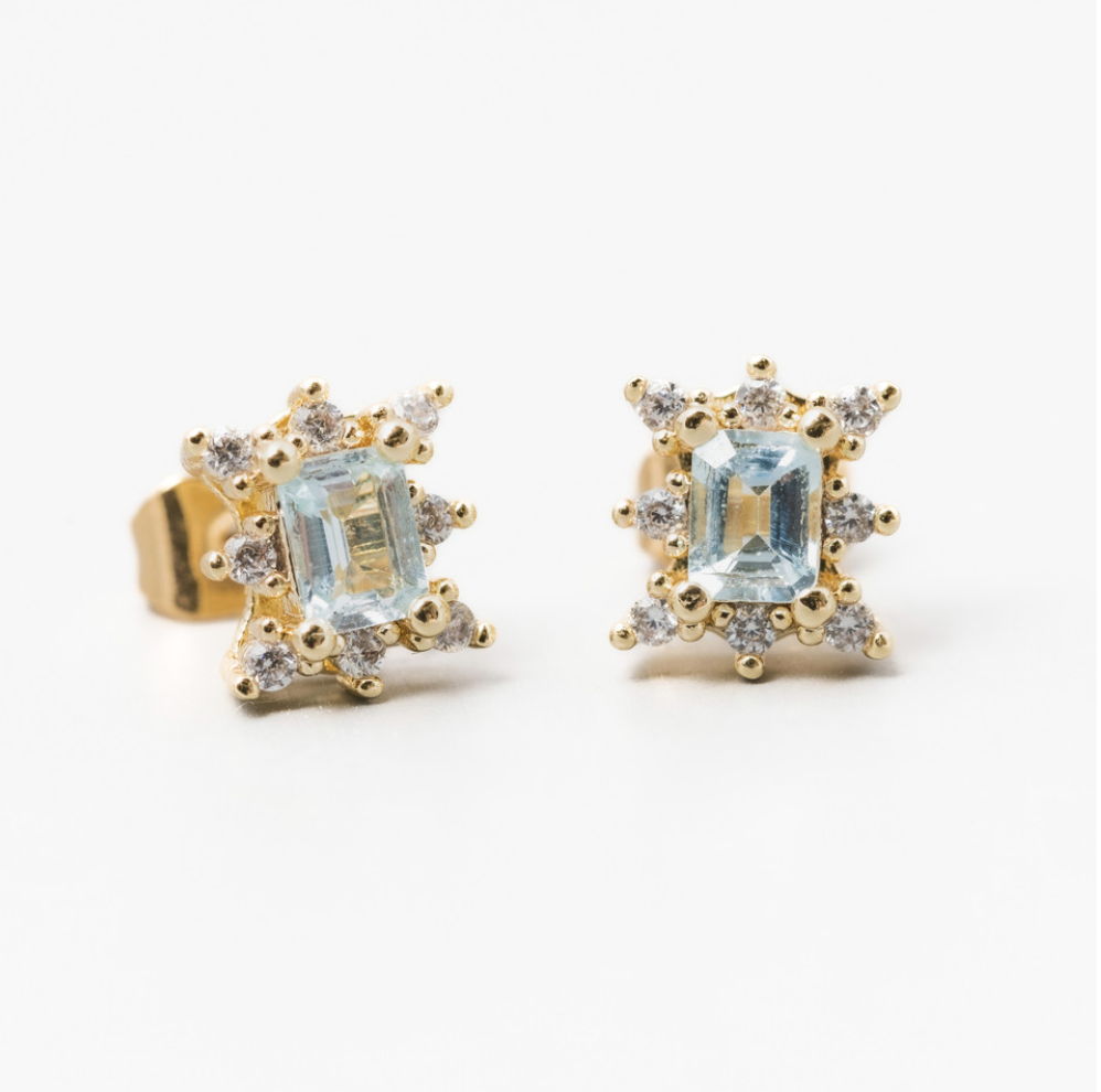 Load image into Gallery viewer, gold stud earrings with baguette shaped blue topaz and a halo of white cubic zirconia on a white background
