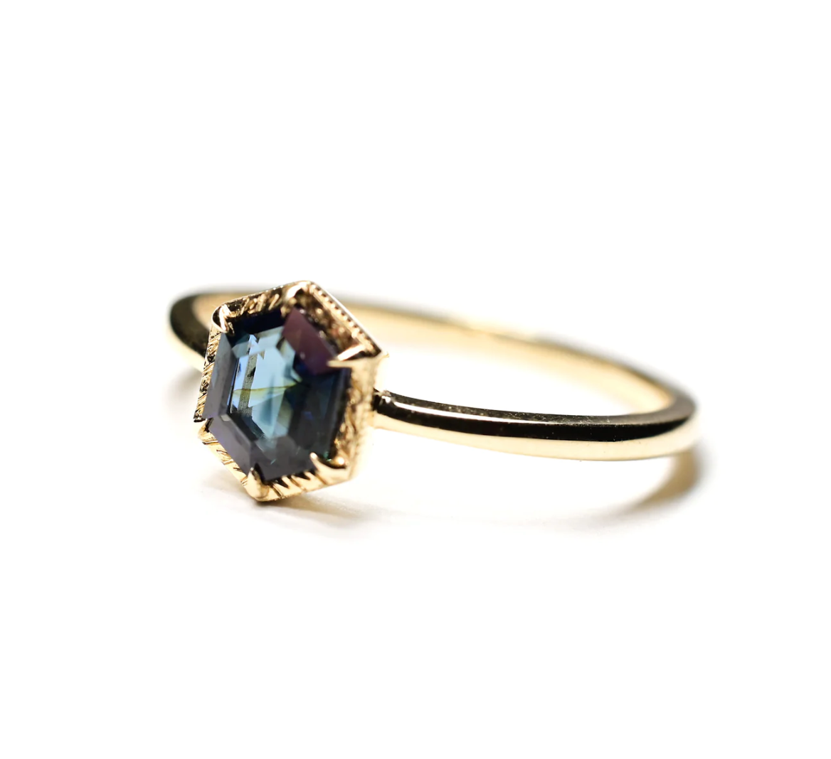 an angled view of the hexagon blue spinel solitaire ring, sitting on a white background