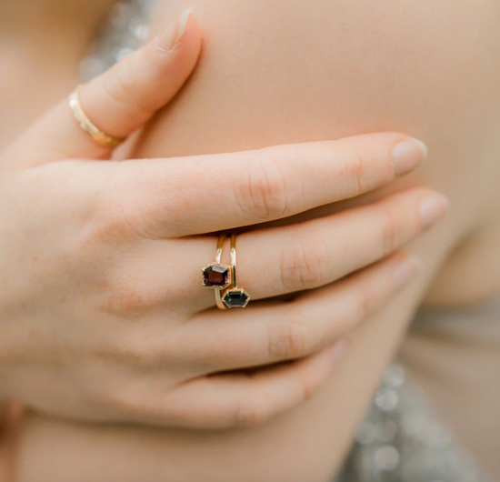 close up of model wearing the fancy purple spinel solitaire on her middle finger stacked with another colored gemstone solitaire