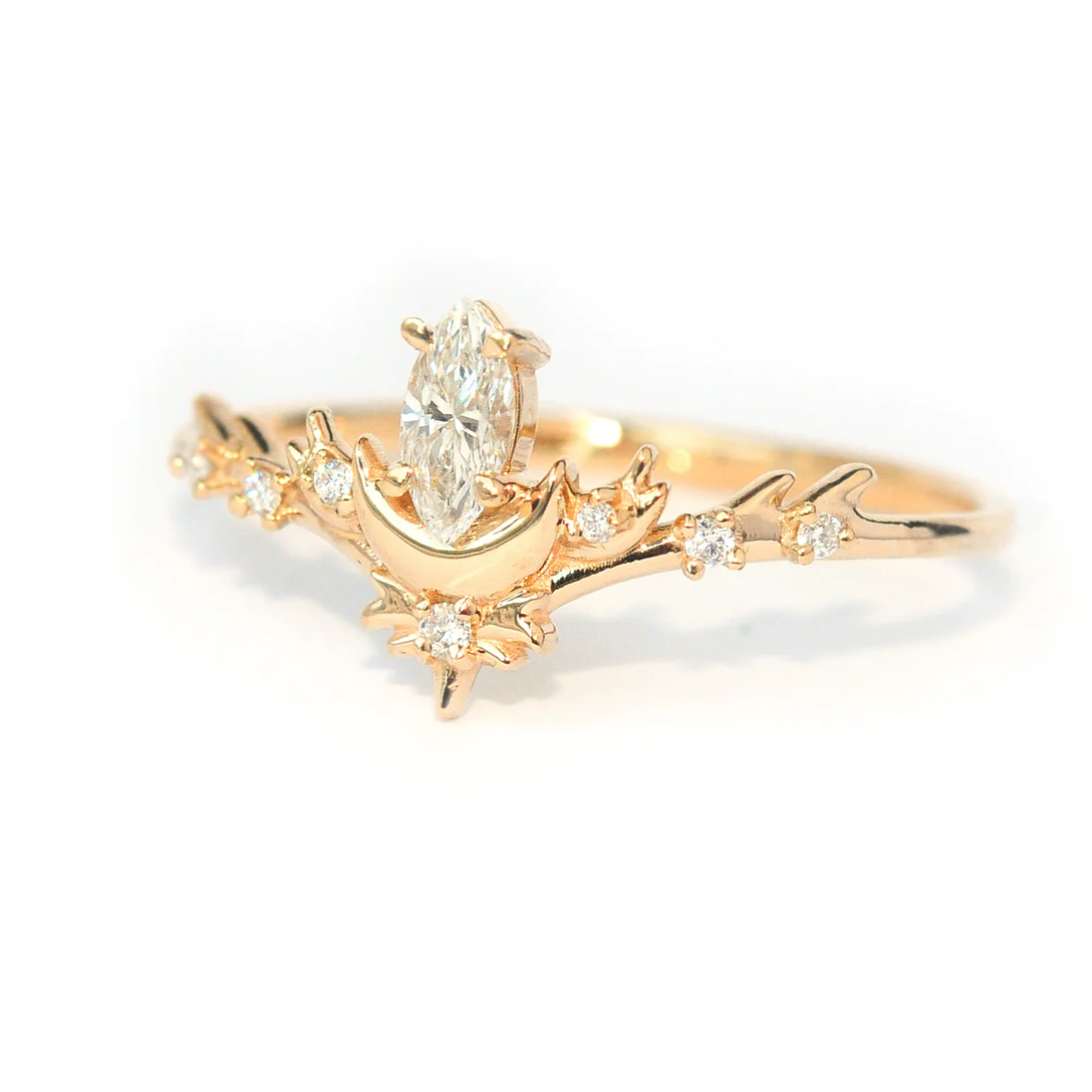 a white marquise diamond sits atop a gold half moon with white diamond melee details