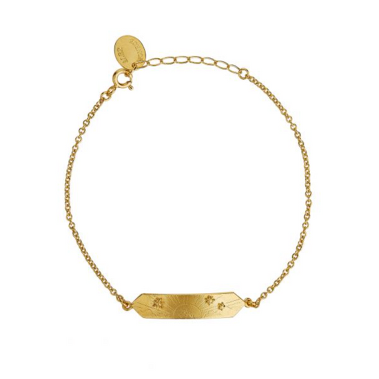gold I.D. bracelet with sun, sailboat, and star engravings on a white background