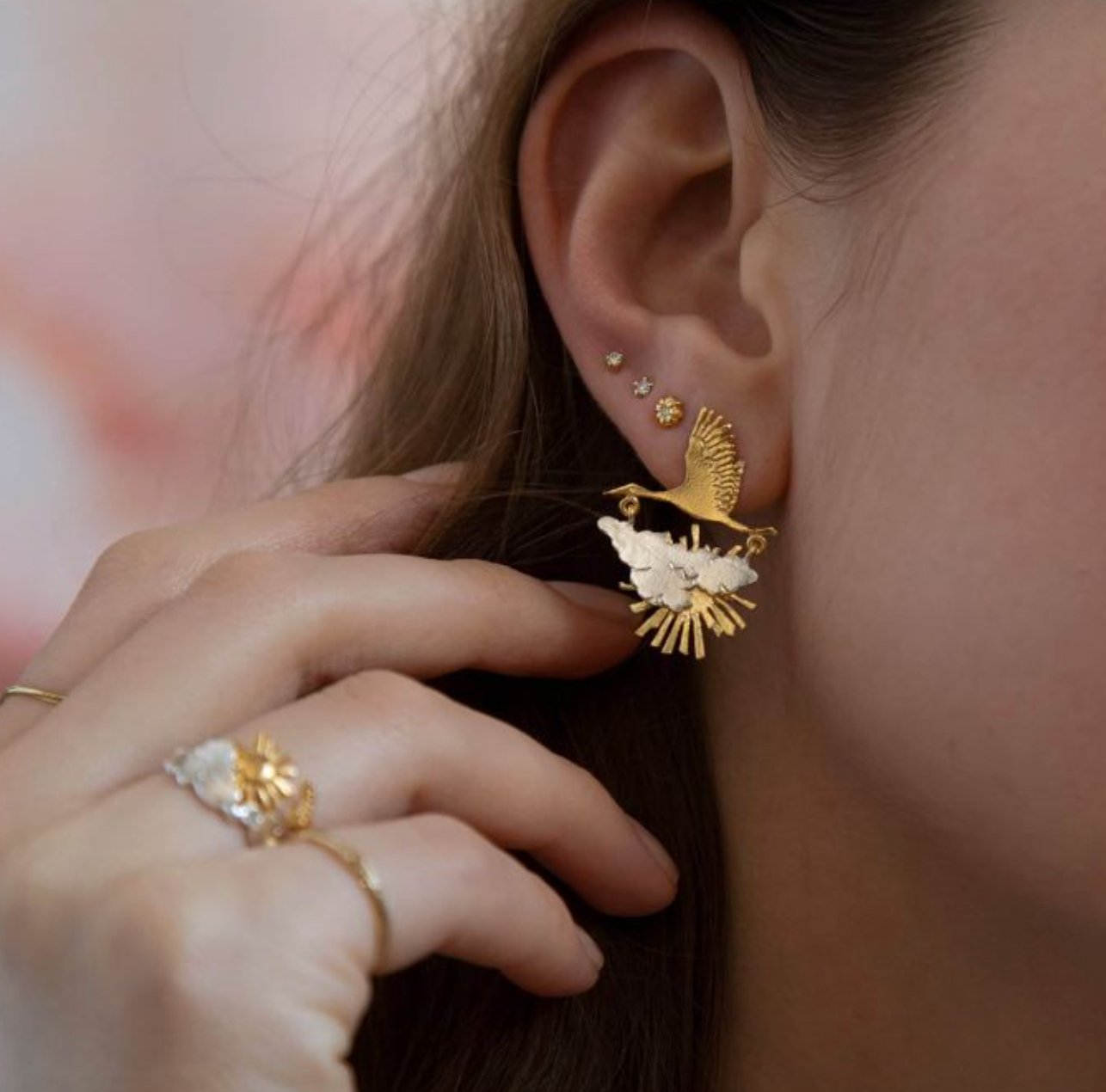 a close up photo of a model wearing the stork in flight earrings