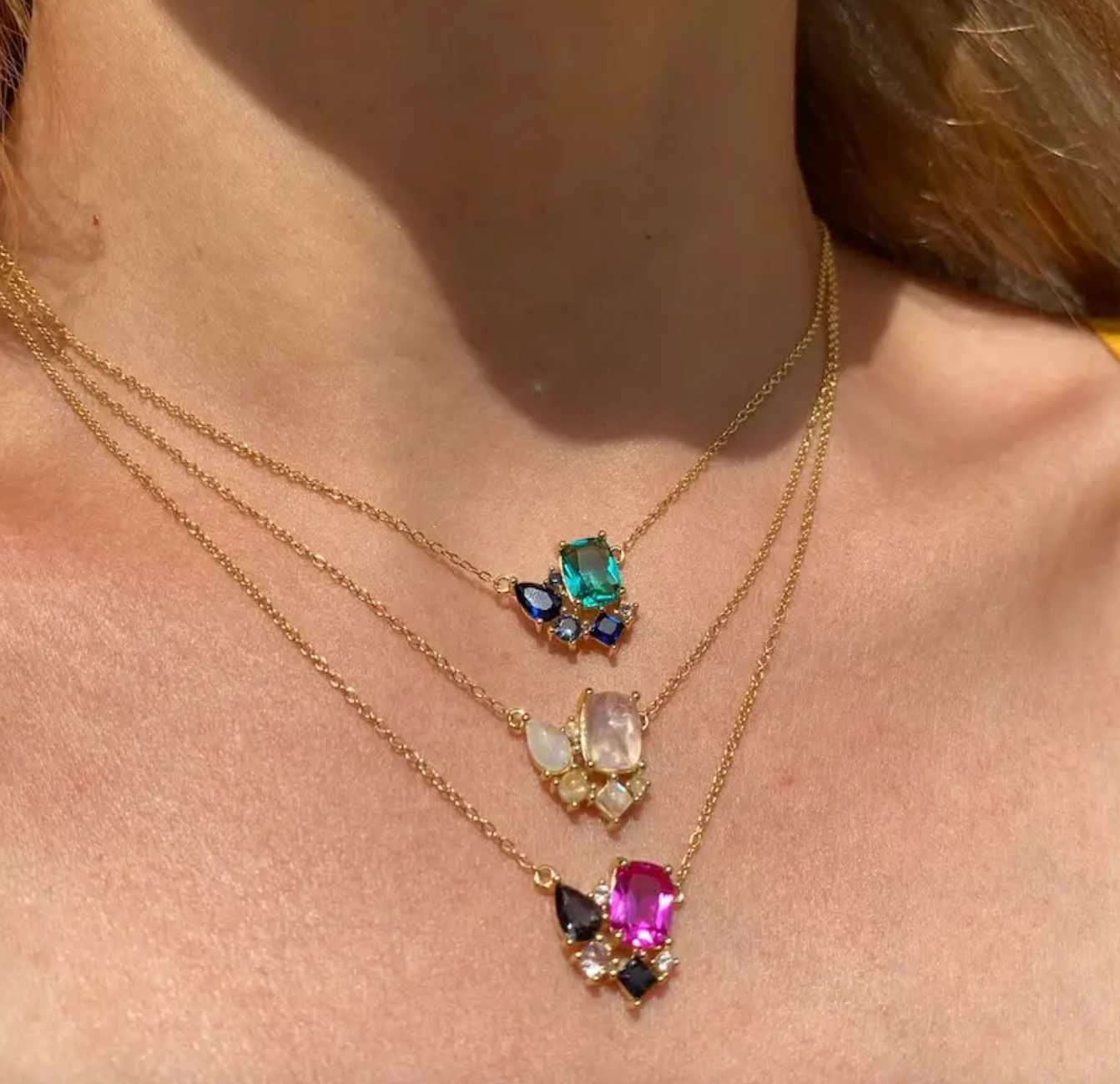 close up of a model wearing three bouquet gemstone necklaces layered together