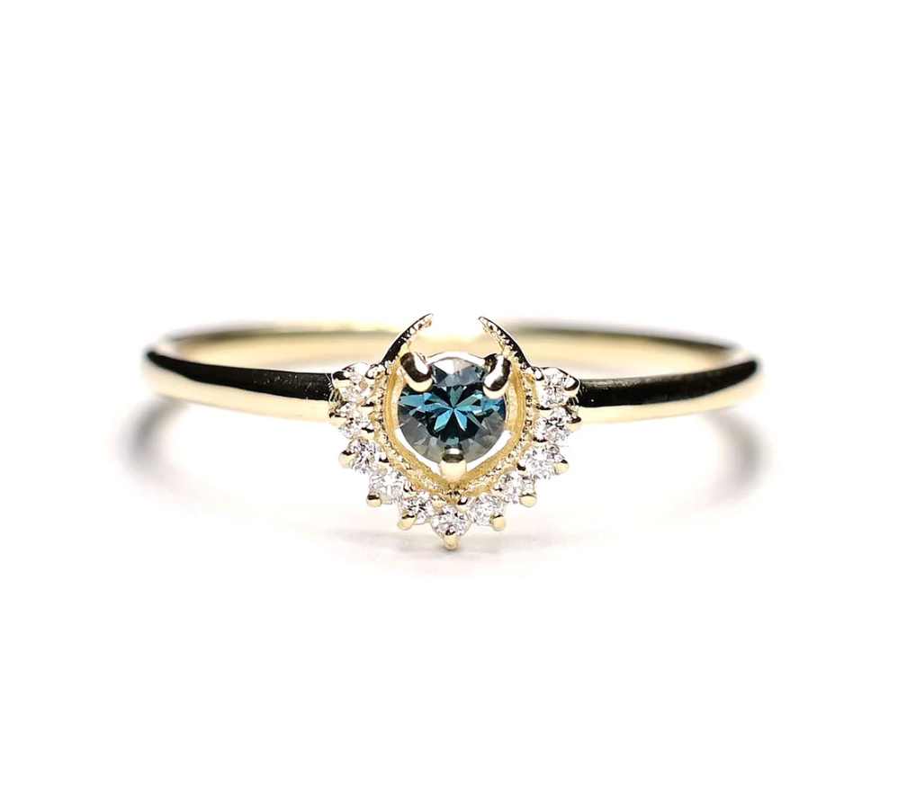 a 14k yellow gold ring with a round blue tourmaline surrounded by diamonds and metal details on a white background