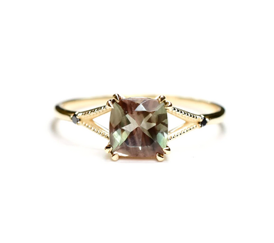 A cushion cut bi colored sunstone split band ring with black diamond and milgrain accents on a white background