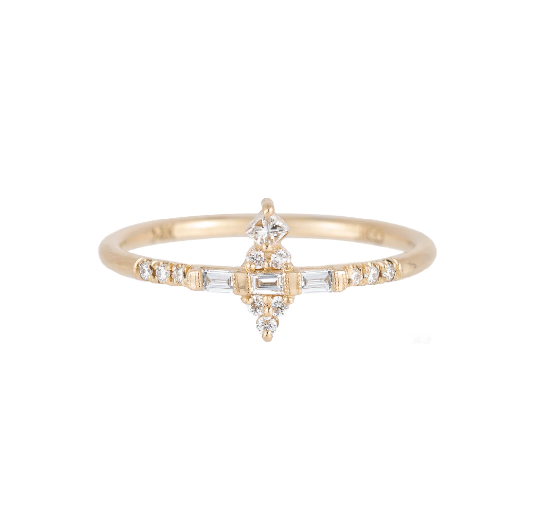 a 14k yellow gold ring with a mix of baguette and round white diamonds set on a white background