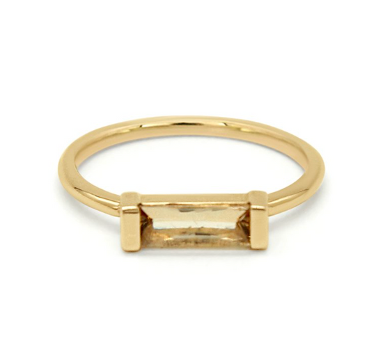 a golden baguette bezel set in a 14k yellow gold solitaire on a white background