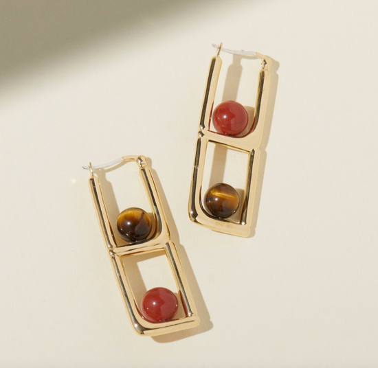 gold statement earrings with round tigers eye and red jasper on a beige background