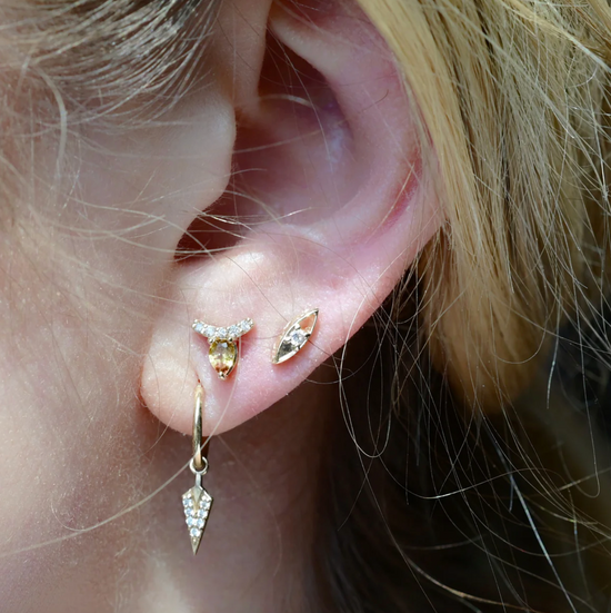 close up of a model wearing the diamond marquise studs in their third ear piercing