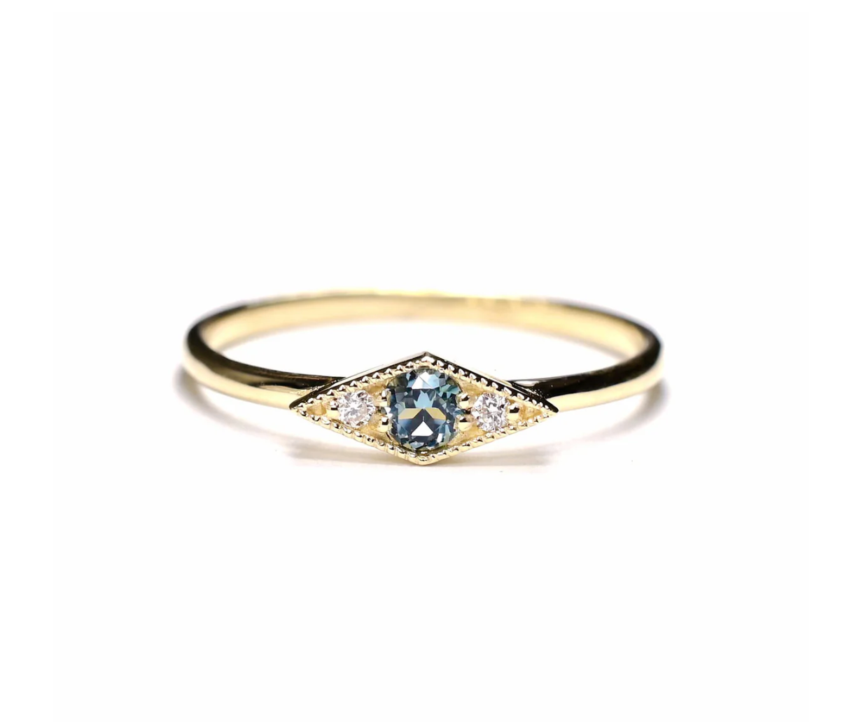 the shillay ring with a blue tourmaline center and two round white diamonds on a white background