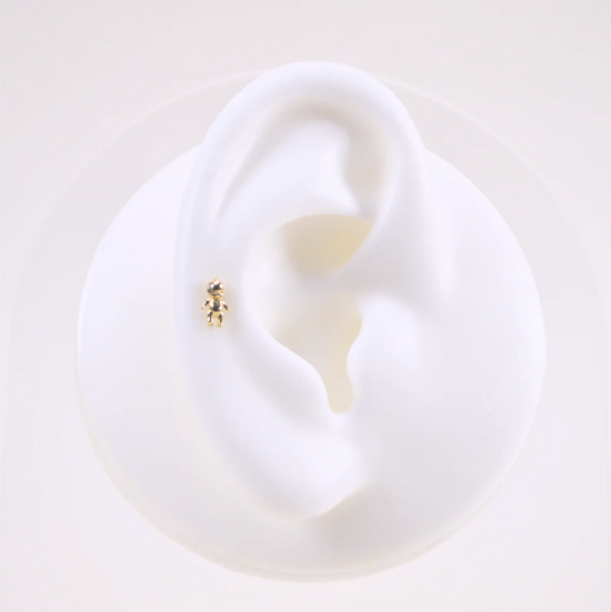 white silicone ear wearing the gold kewpie baby stud earring on a white background
