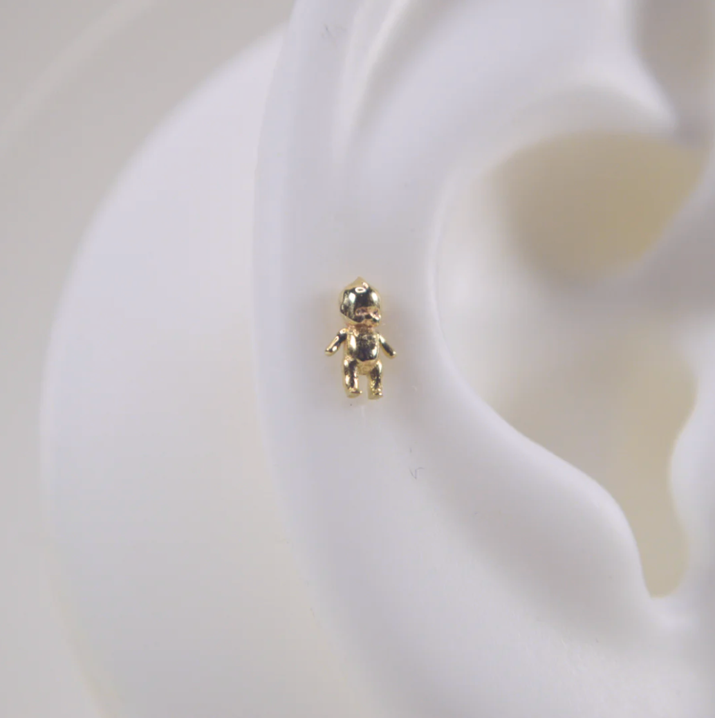 close up of the white silicone ear wearing the gold kewpie baby stud earring
