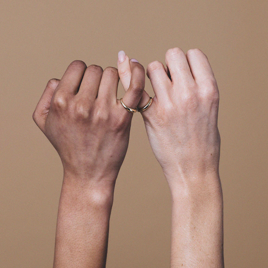 close up of two models wearing the pinky promise ring on their interlocking pinkies