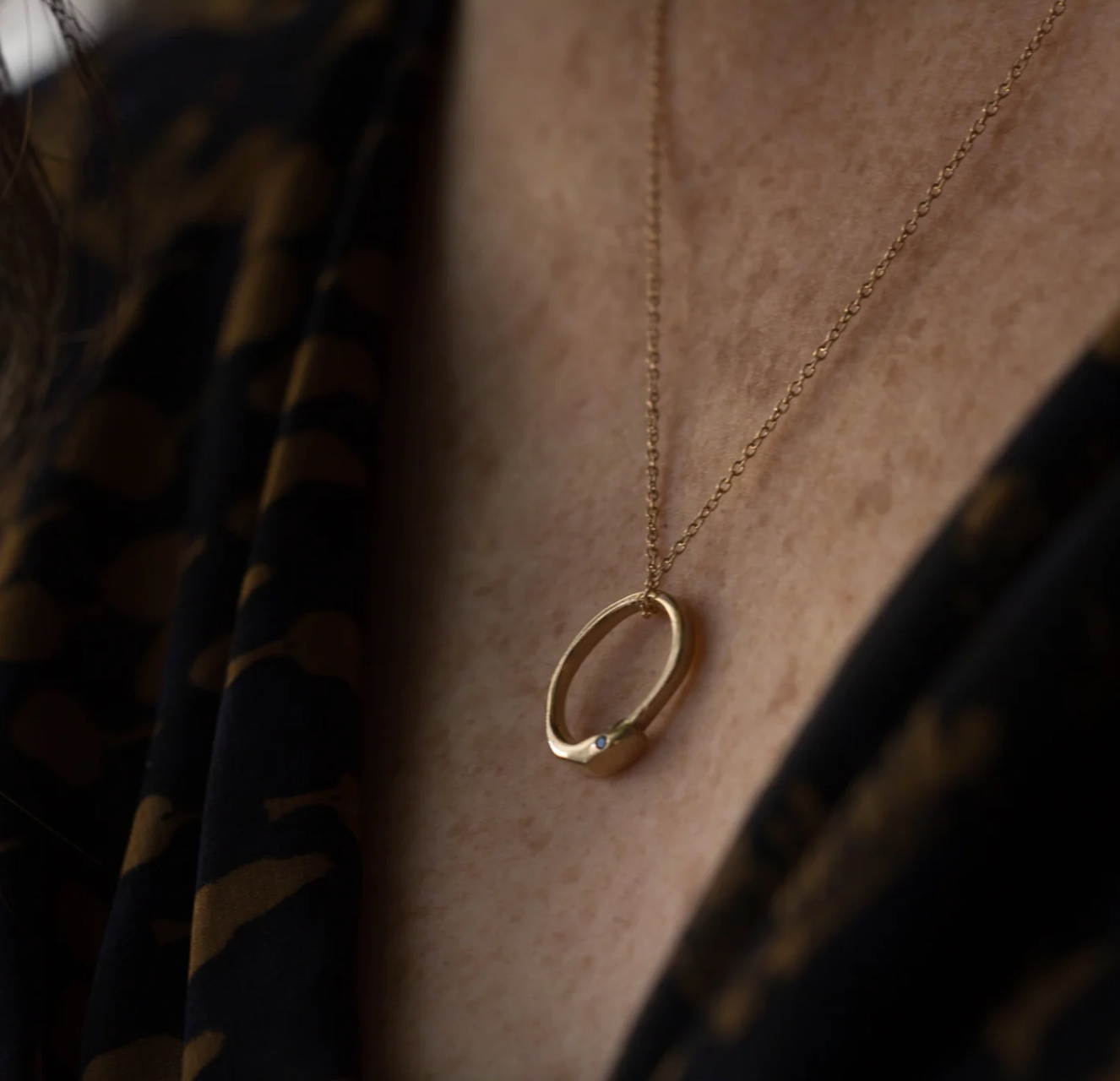 close up of a model wearing the petite ruby ouroboros charm