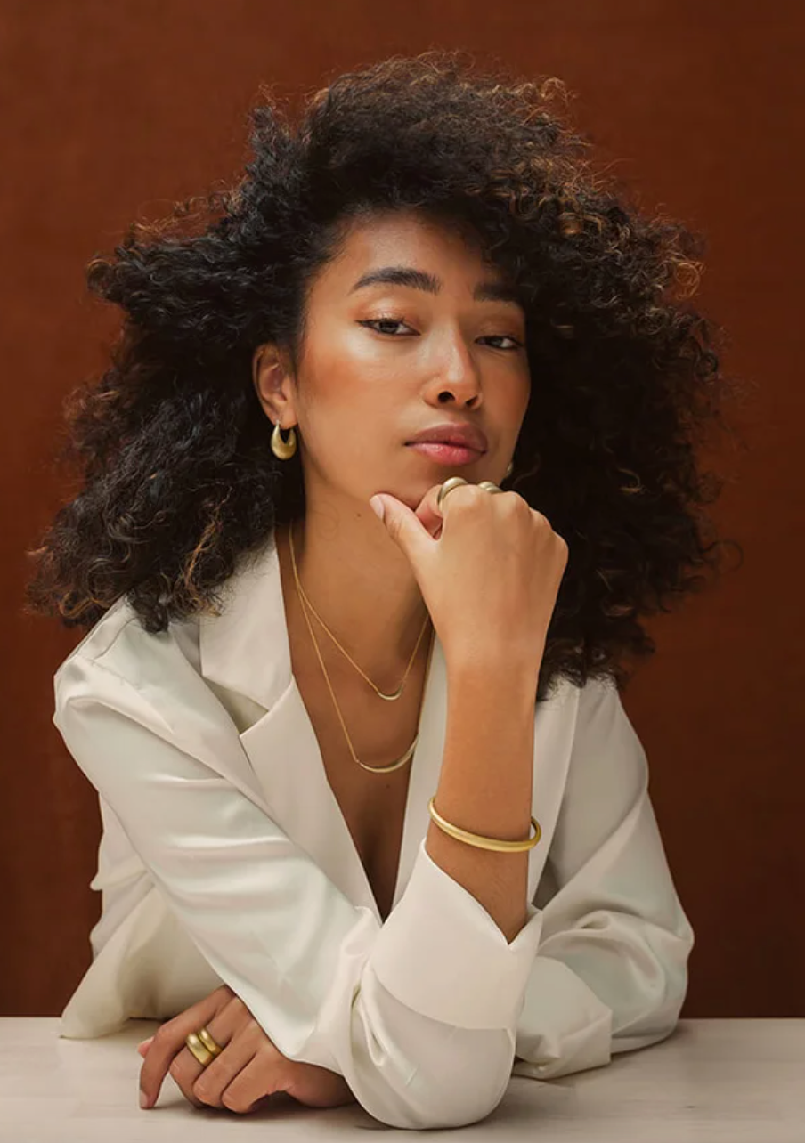 model wearing the curve cuff bracelet along with two necklaces, hoops, and two rings stacked together