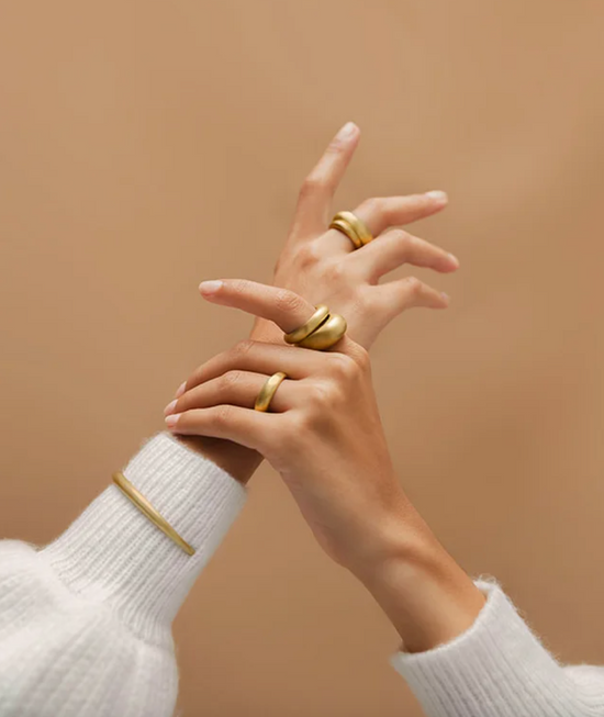 model's hands wearing the oval domed ring on pointer finger stacked with another band and three more rings on their ring and middle fingers