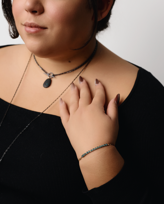 model wearing the beaded gemstone bracelet with two black pendant neckaces