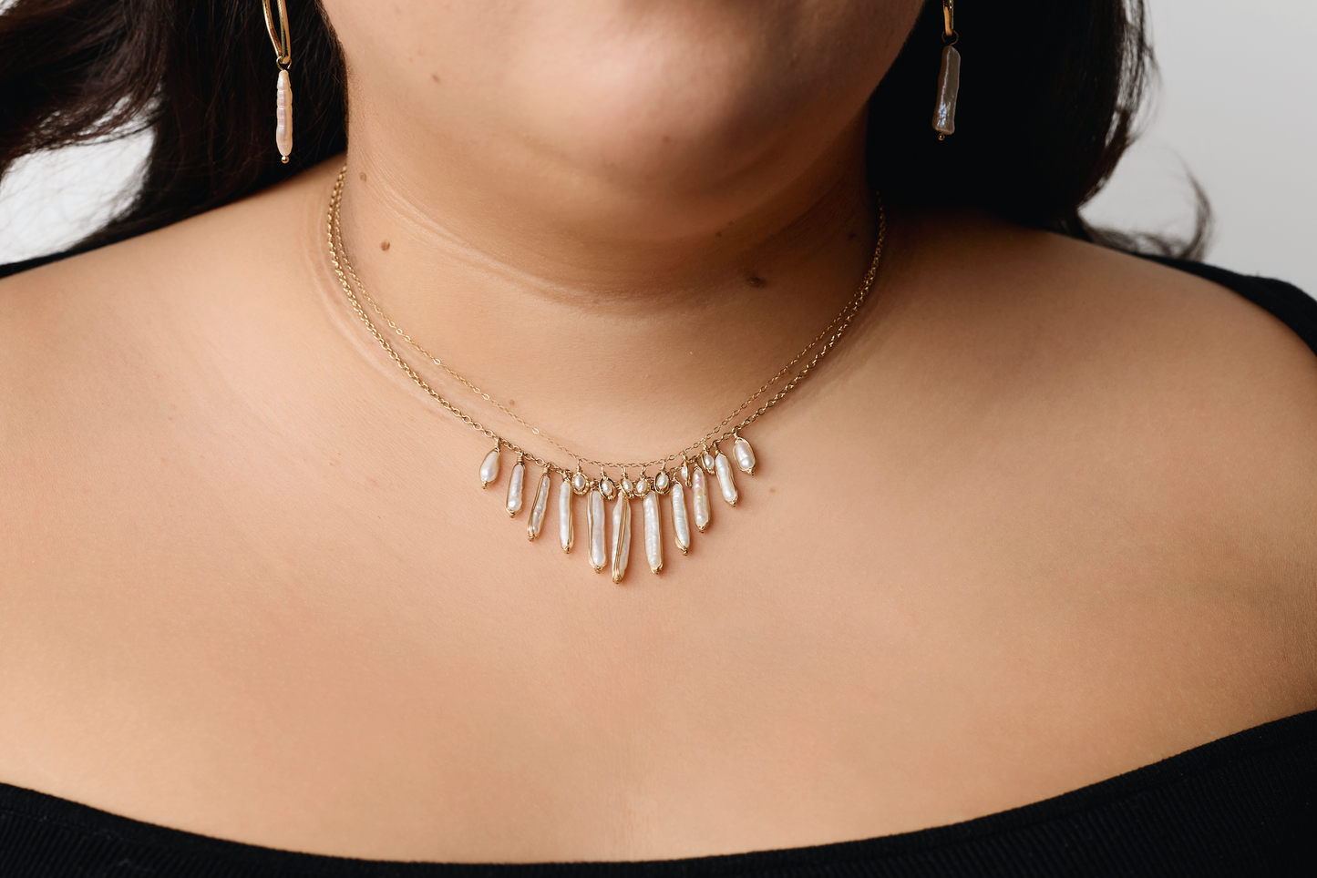 close up of model wearing the pearl stick necklace with another pearl necklace