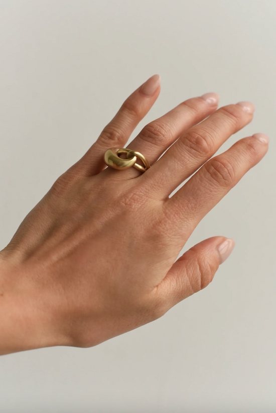 close up of a model wearing the intertwining cloud ring on ring finger with grey background