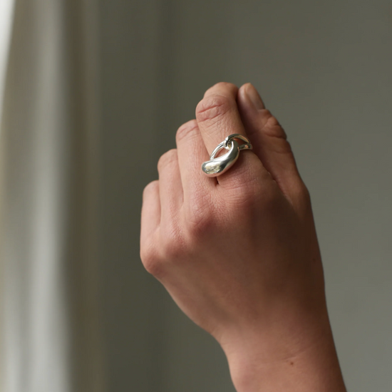 close up of model wearing the silver cloud ring on pointer finger with grey background