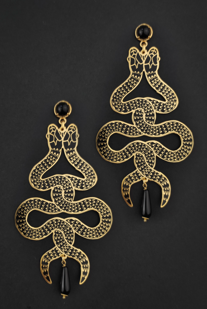 Symmetrical snake earrings with intertwining twin snakes and black onyx gems on a black background