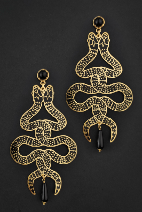 Symmetrical snake earrings with intertwining twin snakes and black onyx gems on a black background