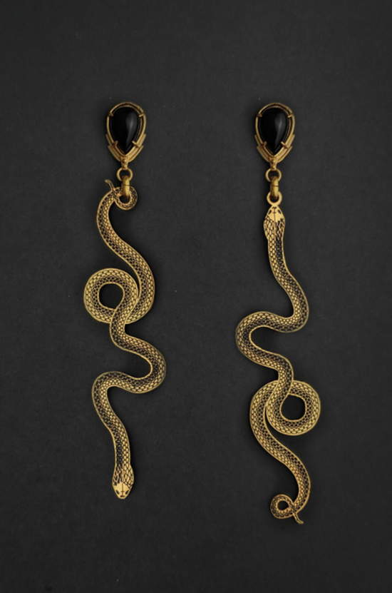 A pair of black and gold earrings with two snakes slithering in opposite directions from a pear shaped black onyx, on a black background