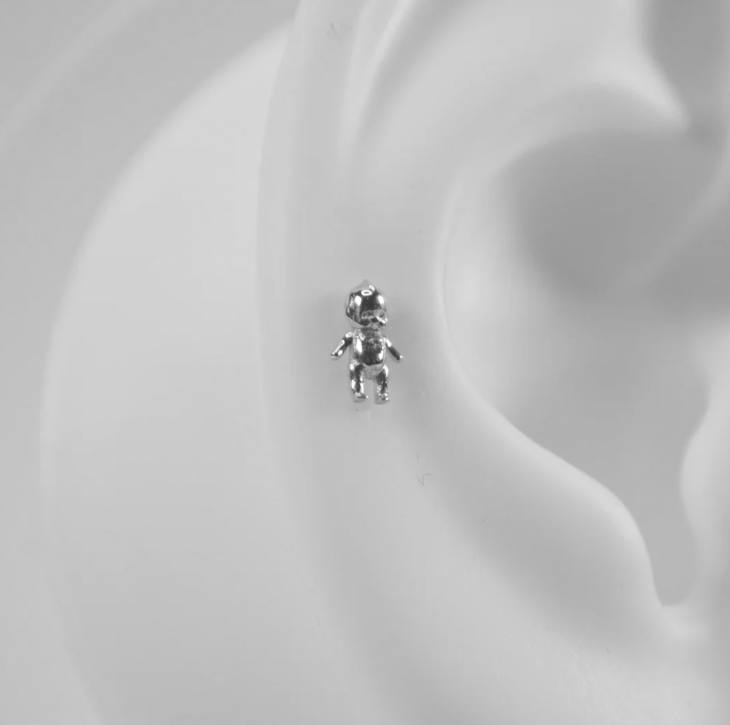 silver kewpie baby stud close up on a silicon ear