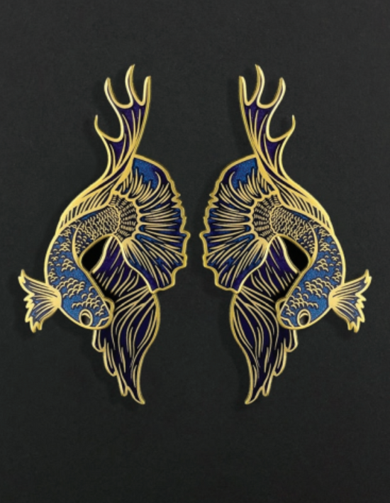 Pair of blue and gold betta fish-shaped earrings on a black background