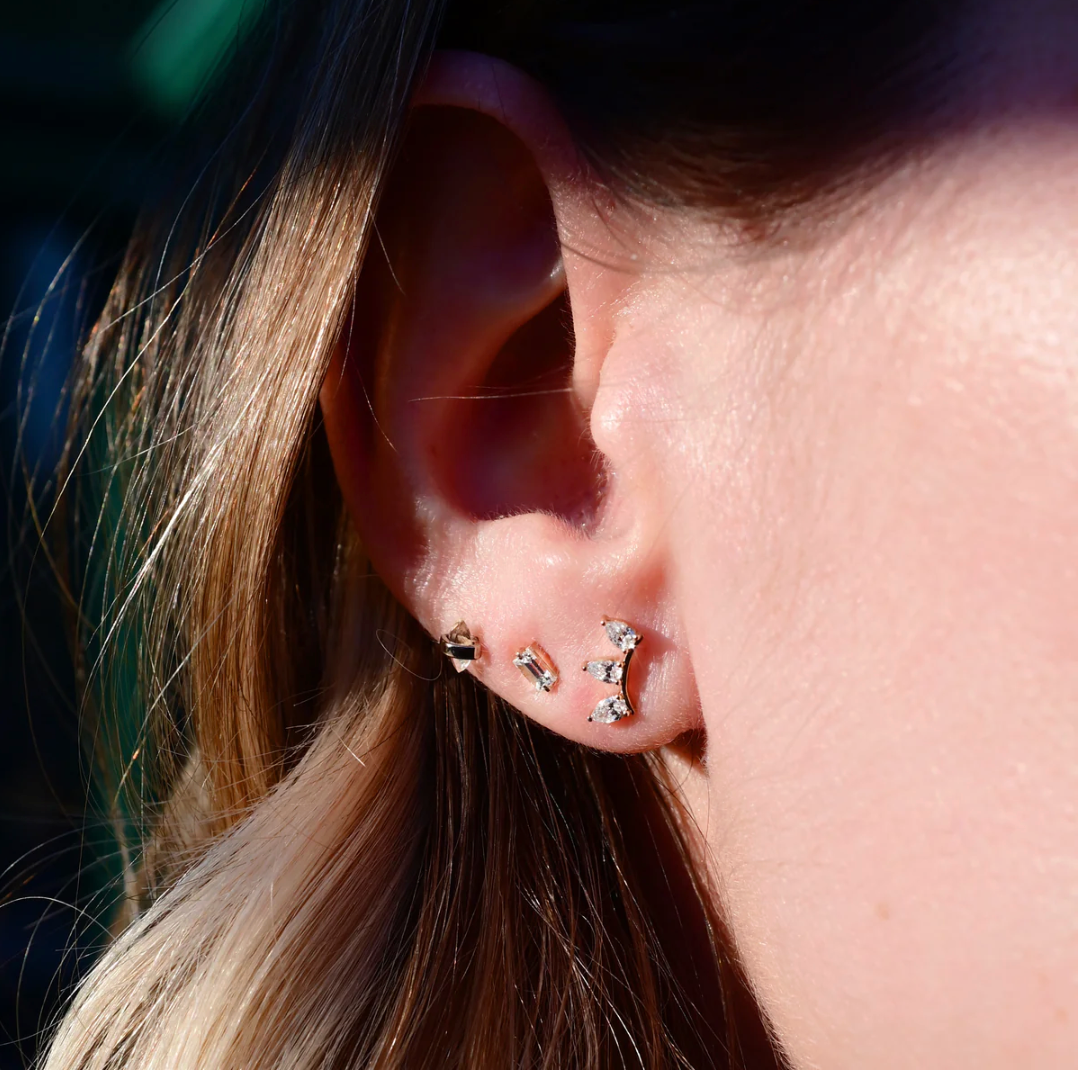 Close-up of an ear wearing a set of earrings with a blurred background