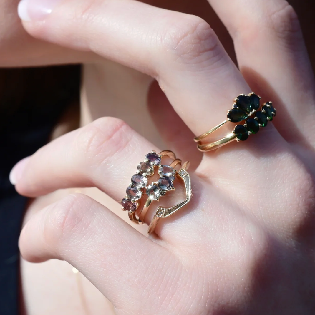 Close-up of a hand wearing two gold rings with gemstones.