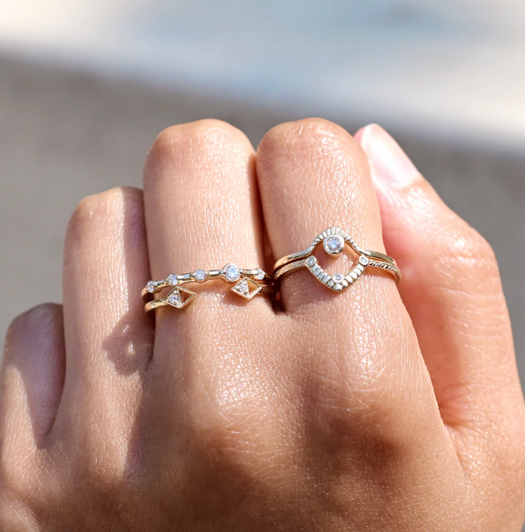 Close-up of a hand wearing four diamond rings with a blurred background