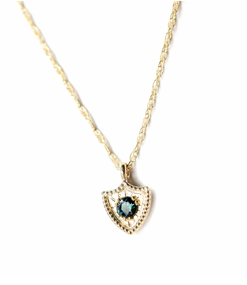 Gold necklace with a heart-shaped pendant featuring a blue gemstone on a white background