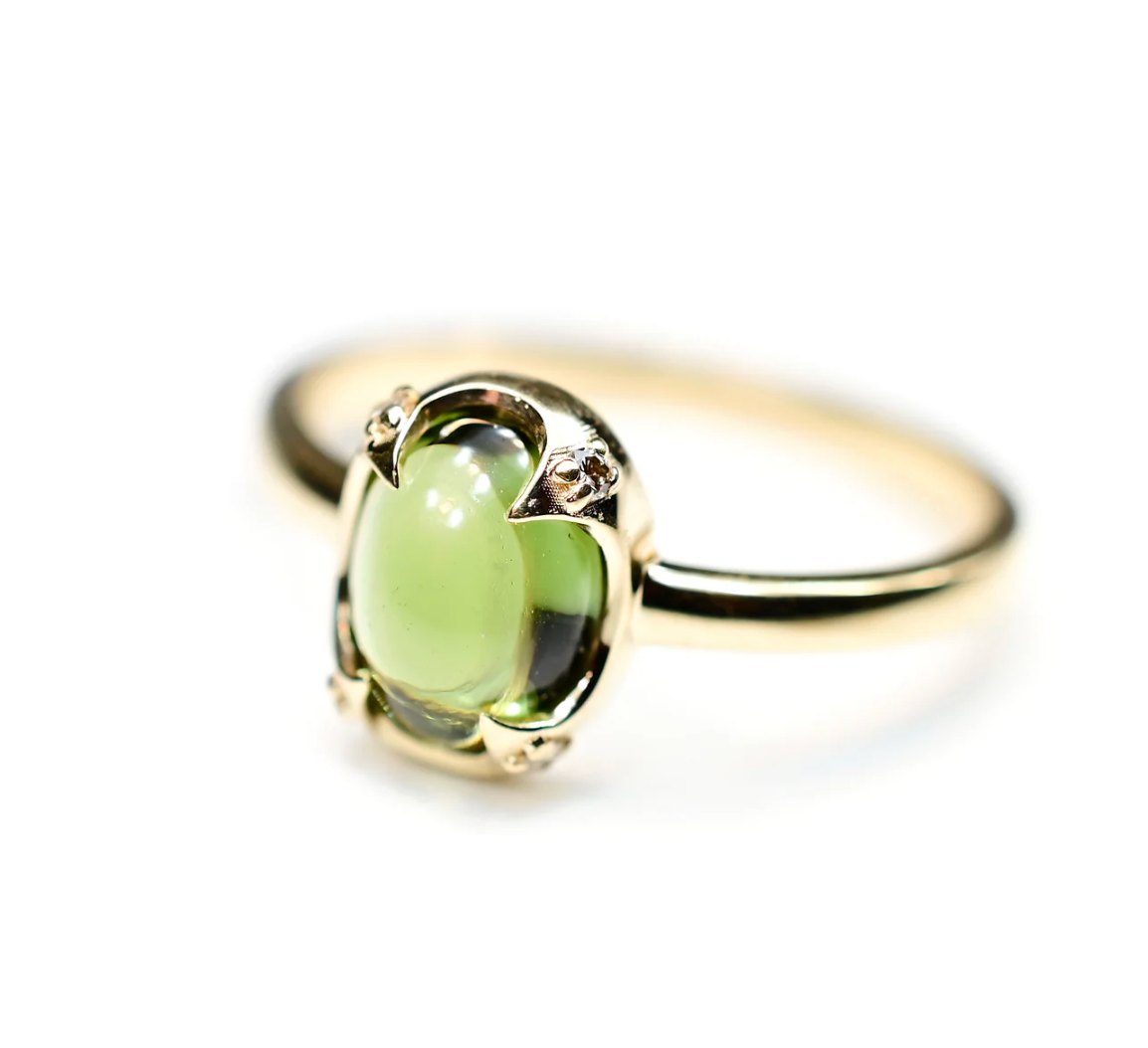 Gold ring with a green gemstone on a white background