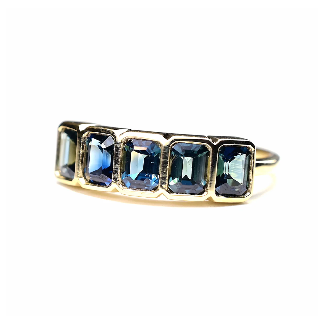 Gold ring with blue gemstones on a white background