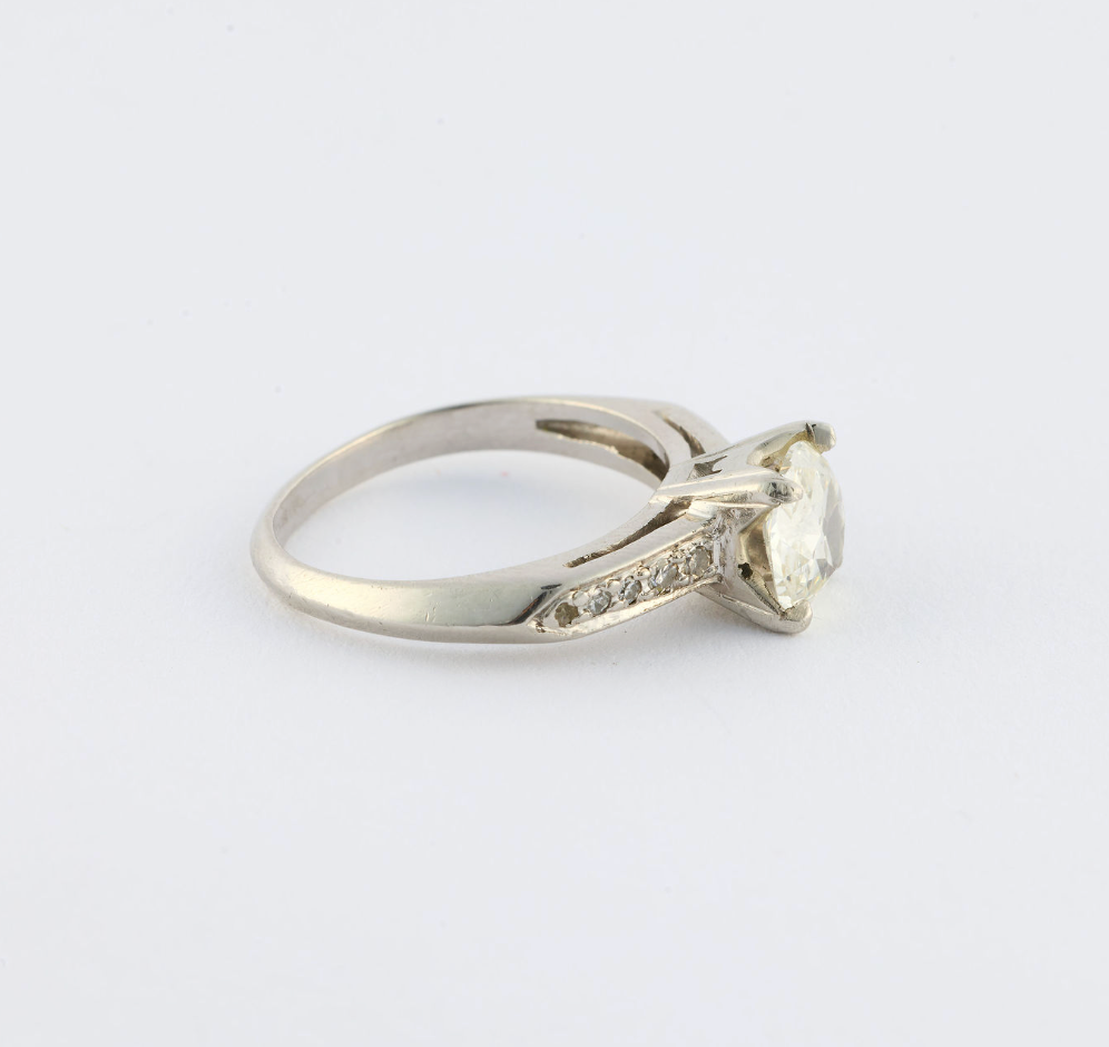 Diamond ring with a white gemstone on a light gray background