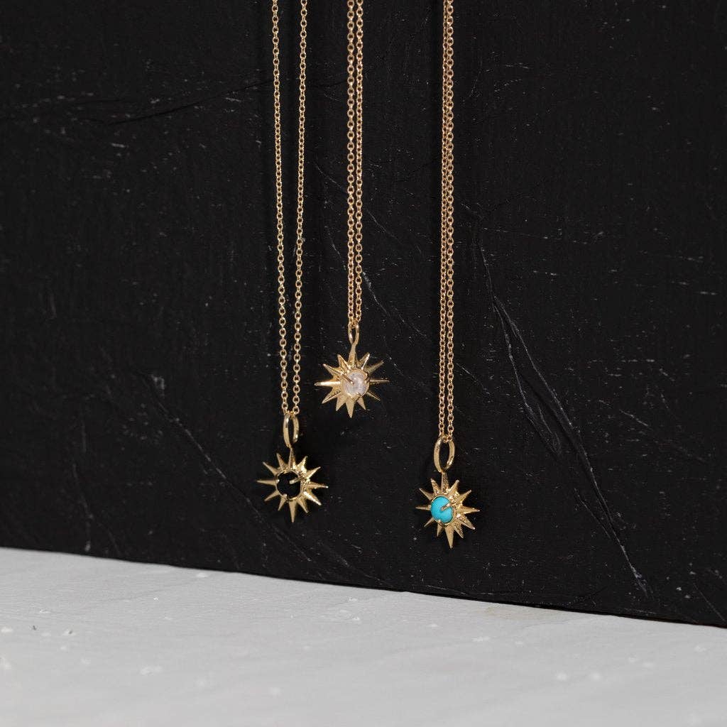 Three gold necklaces with sun-shaped pendants on a black background