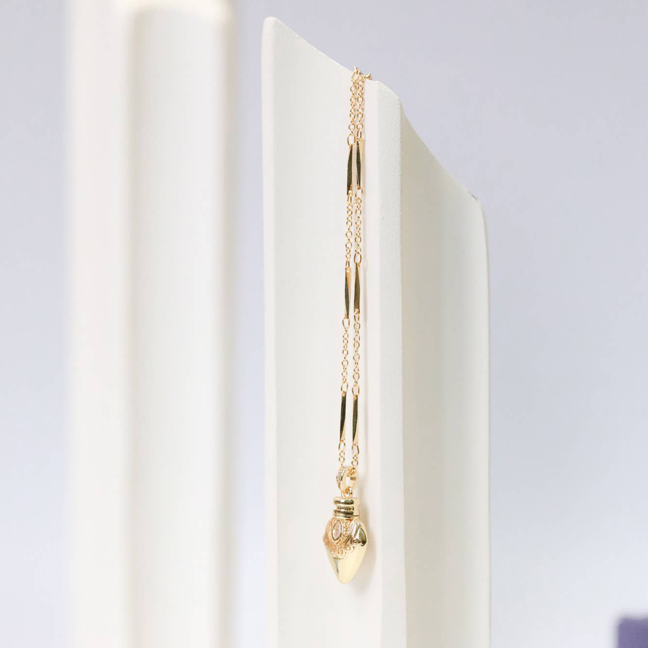 Gold necklace with a pendant on a white surface