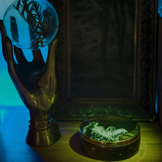 moon angel trinket box on a wood table next to a brass hand holding a crystal ball