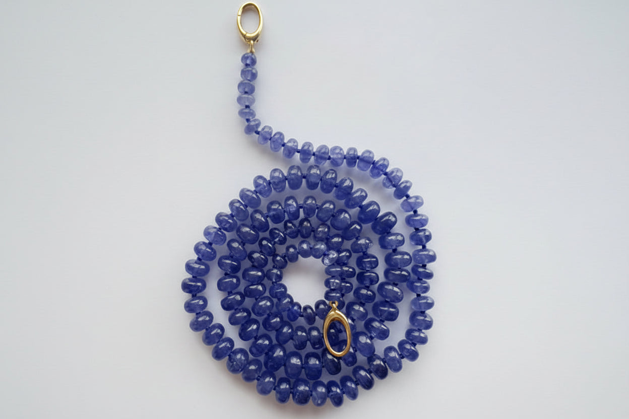 Blue beaded necklace with gold clasp on a white background