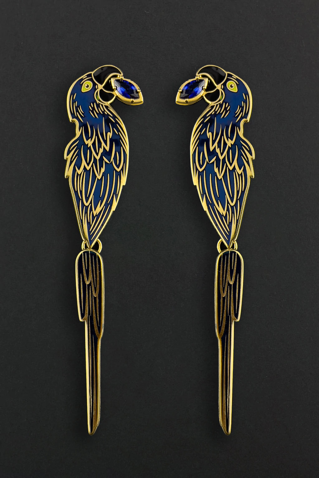 Two decorative macaw earrings with gold and blue details on a black background