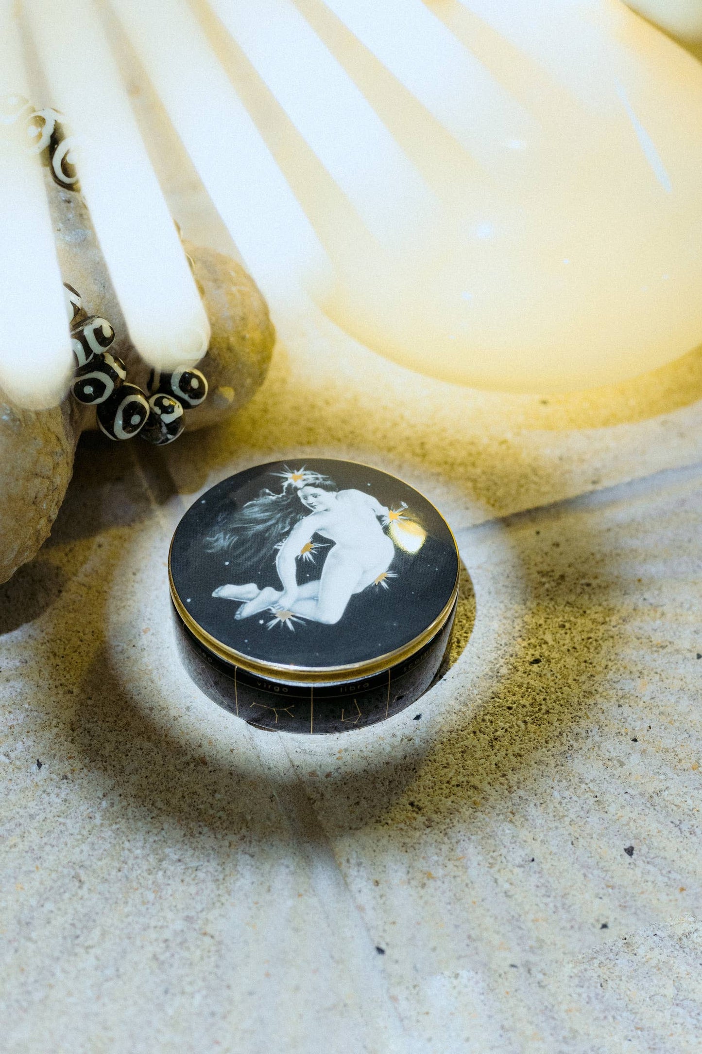 the astrological ceramic trinket dish underneath a yellow light on a stone background