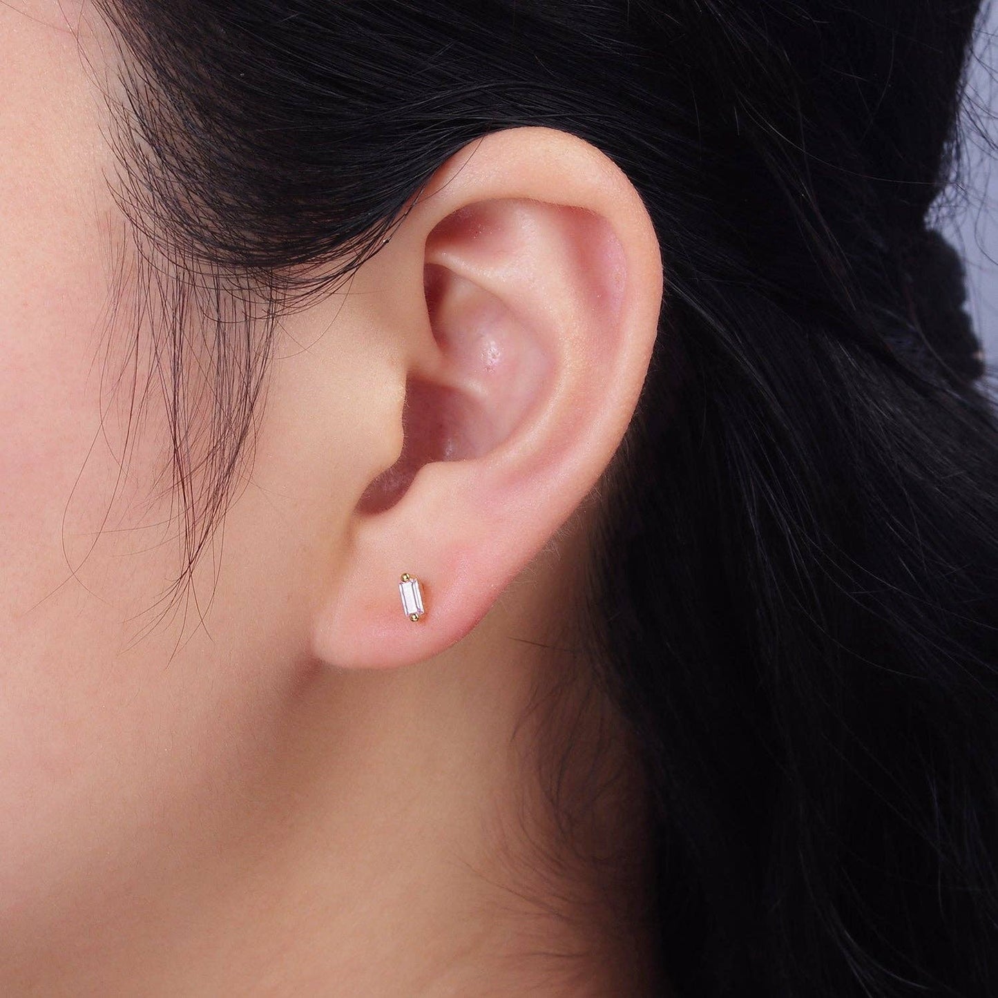 Close-up of an ear wearing a small earring with a dark background