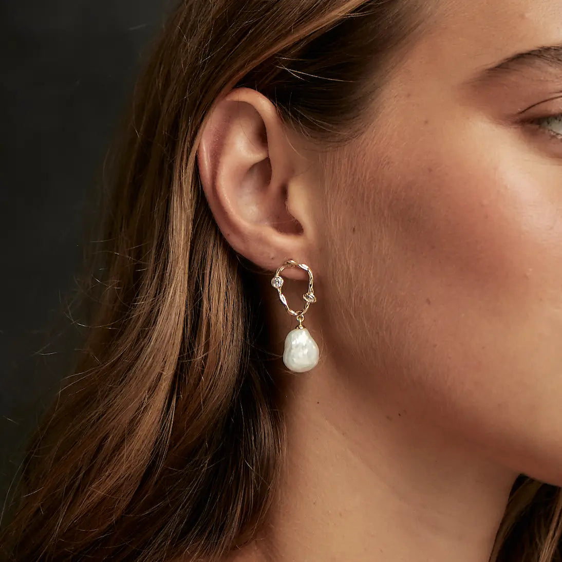 close up of a model wearing the freeform pearl and crystal earrings