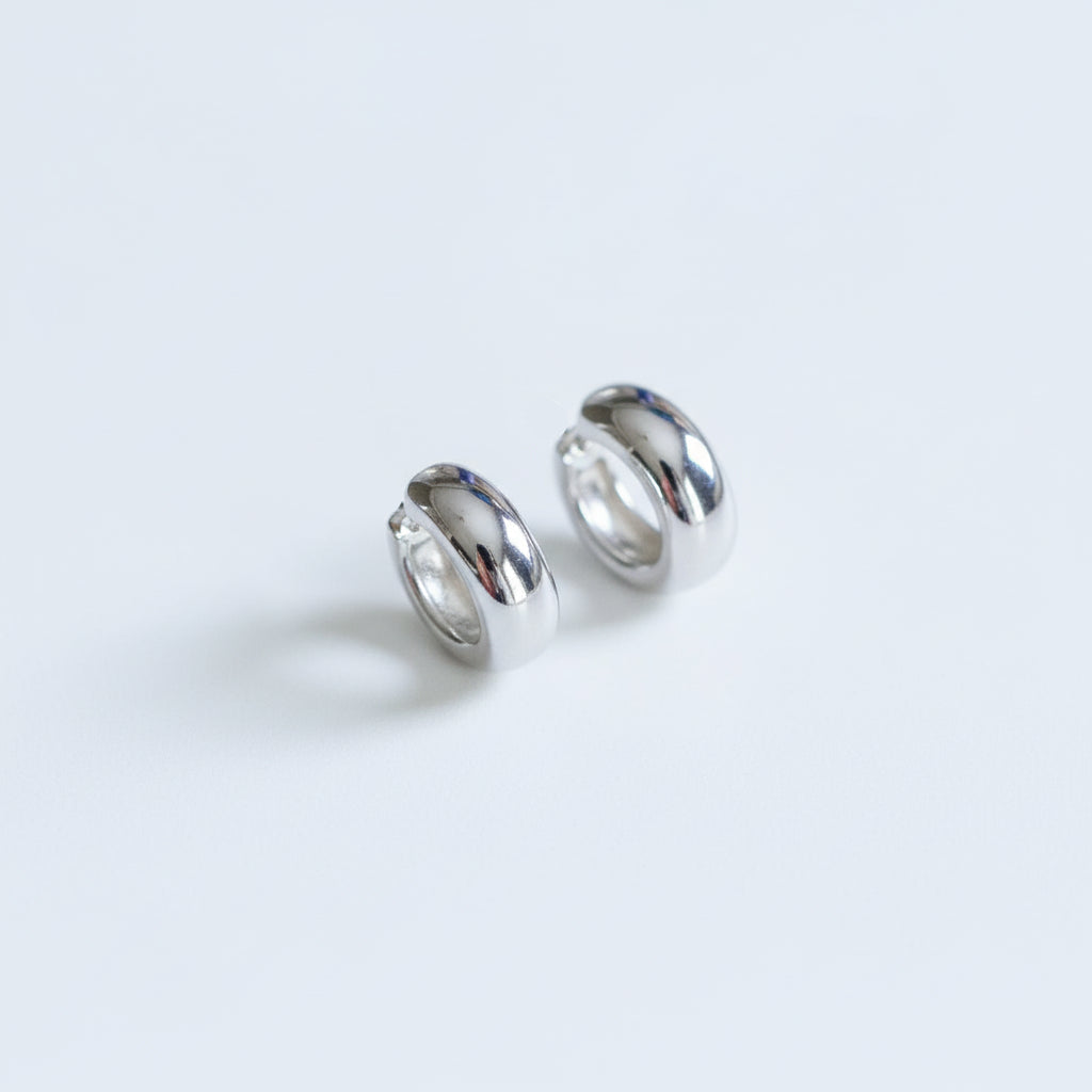 Pair of silver hoop earrings on a textured beige surface