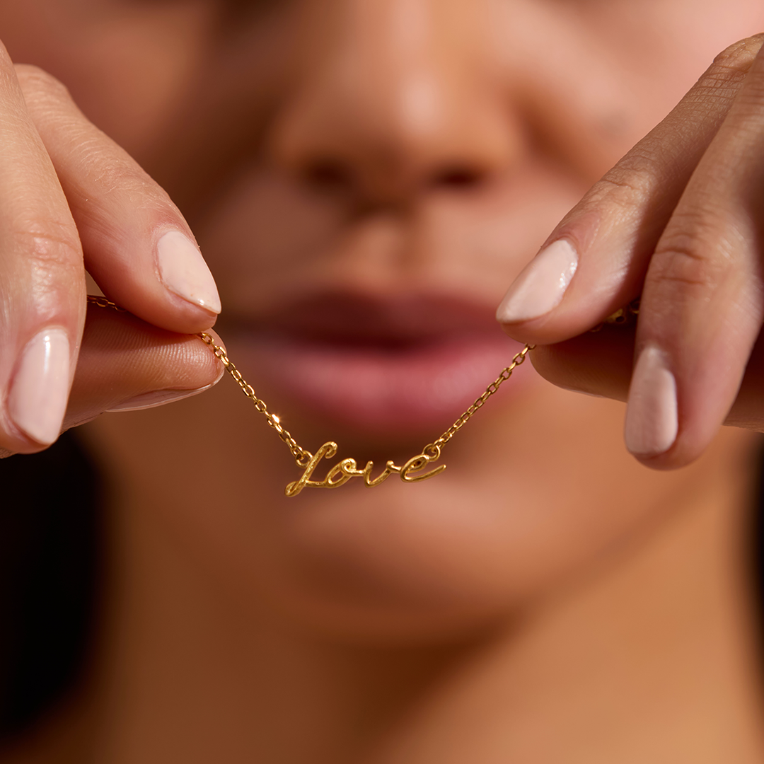 model holding the love necklace so you can see the pendant love up close