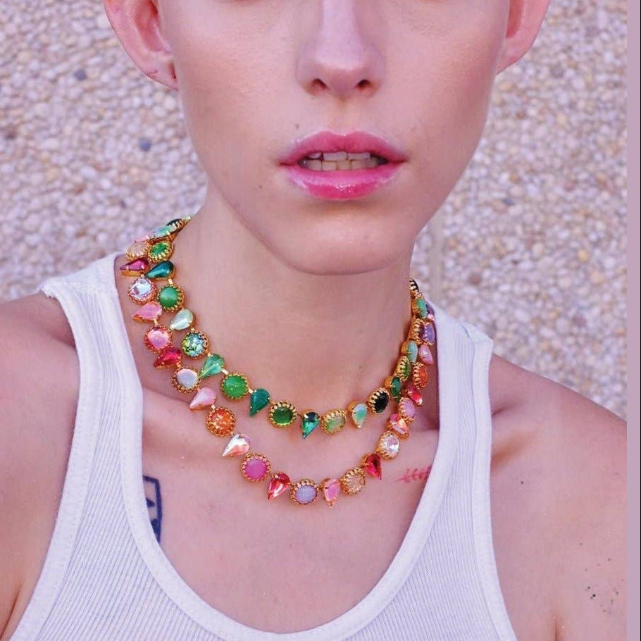 Person wearing a colorful necklace with a textured wall background