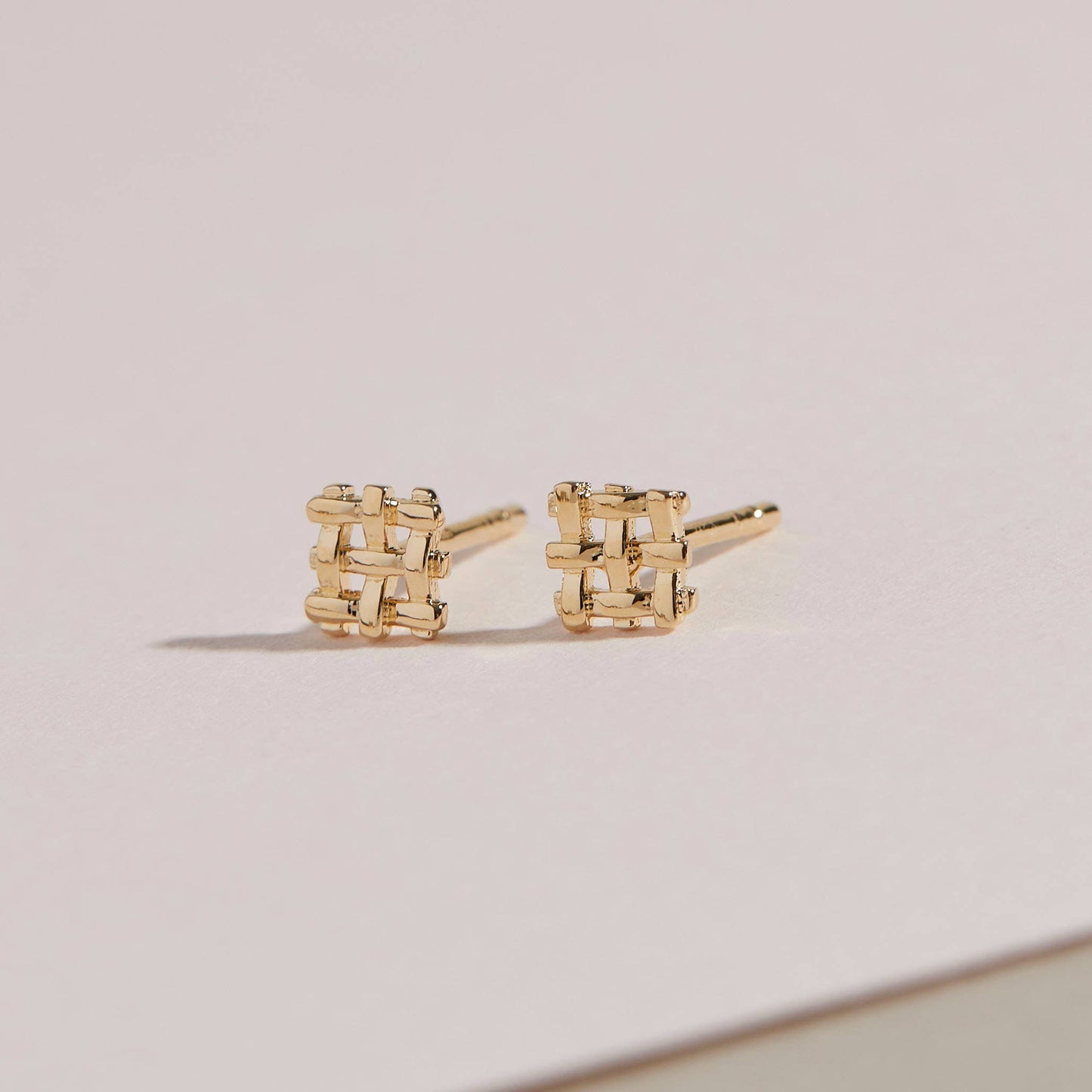 a pair of the crosshatch studs on a beige background
