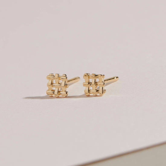 a pair of the crosshatch studs on a beige background