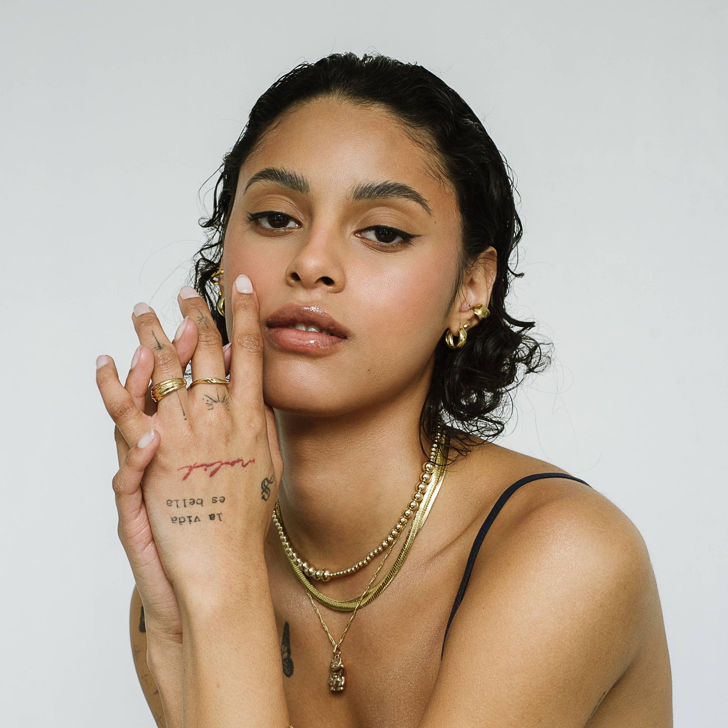 Woman with jewelry and tattoos against a white background